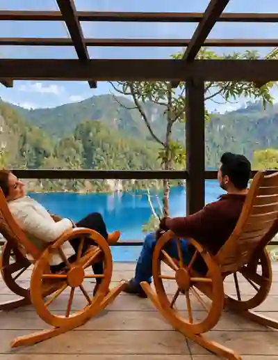 Pareja descansando en sillas de madera frente al lago y las montañas de Montebello.